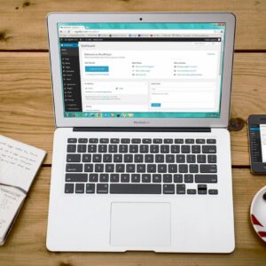 A cozy home office scene with a laptop, notebook, smartphone, and coffee, perfect for productivity.