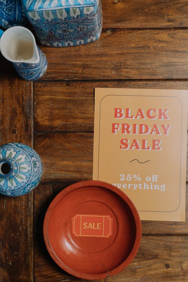 Black Friday sale flyer on wooden table with blue ceramic decor, offering 25% off everything.