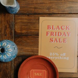 Black Friday sale flyer on wooden table with blue ceramic decor, offering 25% off everything.