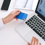 Person making an online purchase with a credit card on a laptop, showcasing modern ecommerce technology.